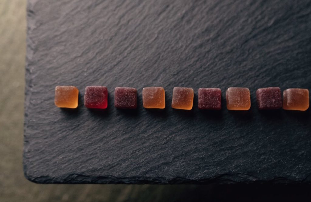 A row of THC gummies on a slate board - Bud Cargo